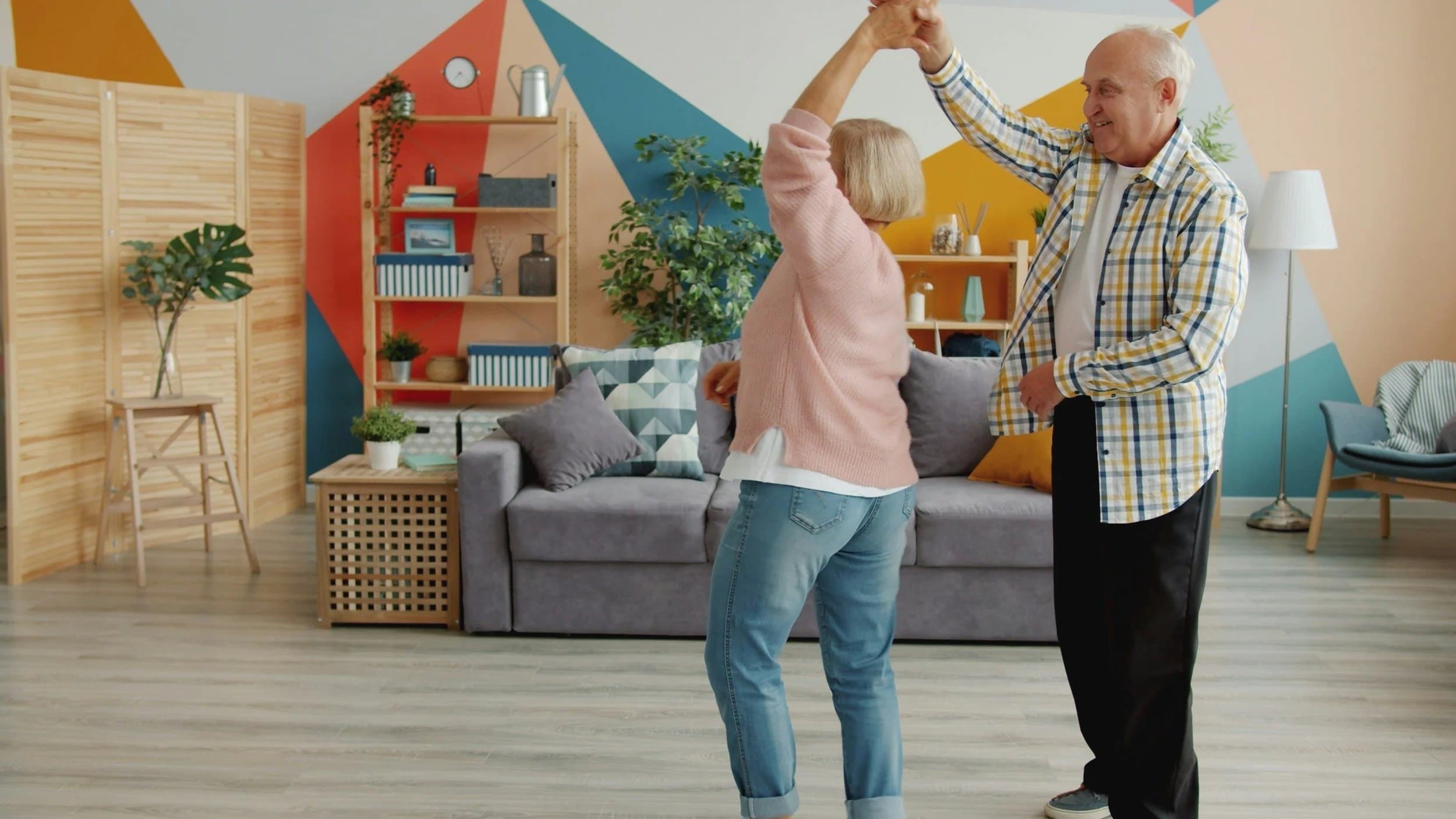 A senior couple dancing together in their bright, colorful living room